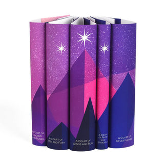 A pink and purple mountain range spans book spines set against a starry sky. Three stars sit atop the highest mountain. Book titles centered at bottom of each book cover in white sans serif font.