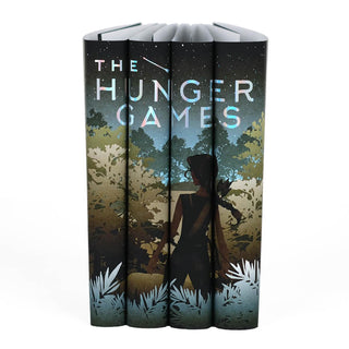 A girl with a bow and arrow standing in front of dense foliage. Limited edition Hunger Games collectible custom dust jackets from Juniper Books.