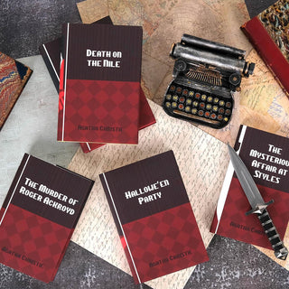 Detail shot of of dust jacket covers. Books sit against a stone background surrounded by maps, letters, antique leather books, typewriter, and a knife. 