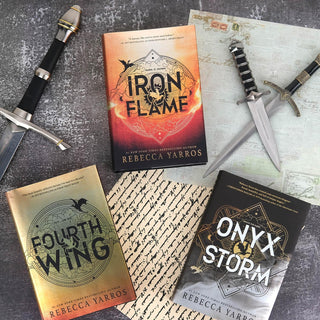Three books by Rebecca Yarros ('Iron Flame', 'Fourth Wing', 'Onyx & Storm') with swords and knives on a textured surface.