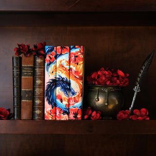 The Poppy War Trilogy R F Kuang Metallic Foil Book Set sitting on a dark wood shelf surrounded by a bronze bowl overflowing with red poppies, antique leather books, and scattered poppy flowers.