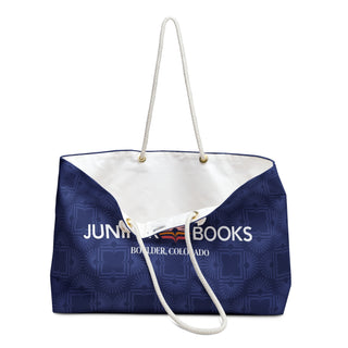 One handle of Juniper Books Book Club Bag rests down to display inside of bag. Inner bag is white canvas.