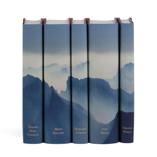 A set of five hardcover books is displayed in a row, each featuring a dust jacket with a blue-toned mountain landscape design that extends seamlessly across all the covers. The books in the set are authored by Virginia Woolf, Joan Didion, Margaret Atwood, Mavis Gallant, and Maxine Hong Kingston, with their names subtly printed on the spines.