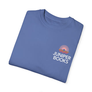 Folded Juniper Books T Shirt in Mystic Blue. Juniper Books logo and company name on left chest in white.