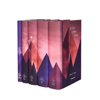 Dust jackets feature pink and purple mountains adorned with three stars span across book spines in the A Court of Thorns and Roses Book Set. Covers feature book title and author name in white serif font against starry background and pink mountains.