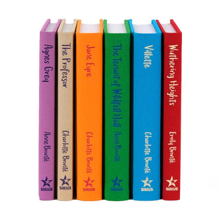 A collection of six hardcover classic novels by the Brontë sisters, displayed upright without their dust jackets. Each book features a vibrant, solid-colored spine with the title and author printed in contrasting fonts. The colors include purple for Agnes Grey, beige for The Professor, orange for Jane Eyre, green for The Tenant of Wildfell Hall, blue for Villette, and red for Wuthering Heights. The Sirius logo is visible at the base of each spine, adding a cohesive branding element.