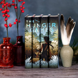 A girl with a bow standing in front of foliage. The Hunger Games limited edition custom collectible dust jackets from Juniper Books.
