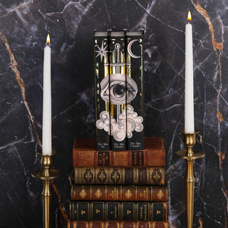 Install shot of The Atlas Series sitting on a stack of antique leather books with candles on either side set against a black marble background.