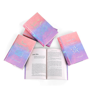 A set of five Ali Hazelwood novels with covers visible featuring custom designed book jackets on a white background photographed from above. One book in the center is open revealing the text within. Each front cover includes the book's title along with various STEM-themed iconography on a background gradient of pink, blue, and purple. The design features a limited edition, shimmering foiling effect.