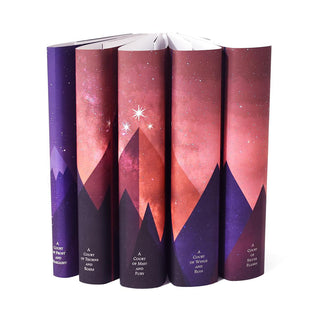 Custom collectible dust jackets feature pink and purple mountains adorned with three stars span across book spines in the A Court of Thorns and Roses Book Set.