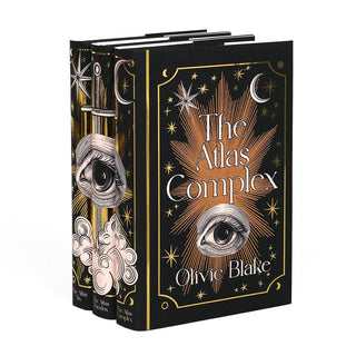 Angle shot of The Atlas Series by Olivie Blake. Dust jacket front covers feature woodcut eye illustration surrounded by gold foil stars and ornamental detailing. Covers feature book title and author name. 