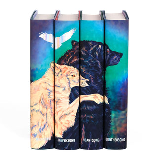 A set of four books displayed together with book covers that create a connected illustration across the spines. The artwork features two wolves embracing, one light-colored and the other dark, set against a vivid, colorful background with shades of teal, purple, and blue. A black bird silhouette in holographic foil flies above the wolves, enhancing the mystical atmosphere. The book titles in the Green Creek series are visible on the spines in holographic foil.