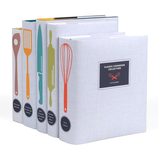 A set of five classic cookbooks with coordinated light gray dust jackets, each featuring a colorful kitchen utensil illustration on the spine, including a wooden spoon, spatula, chef’s knife, rolling pin, and whisk. The front cover of the foremost book displays a black label with white text reading "Classic Cookbook Collection" along with a small red whisk illustration and the title Joy of Cooking.