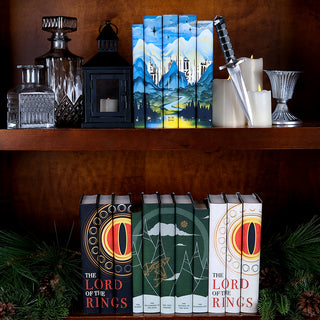 Tolkien's Epic Journey Book set from Juniper Books sitting on shelve above Eye of Sauron Sets and Lord of The Rings Complete book sets surrounded by foliage and candles.