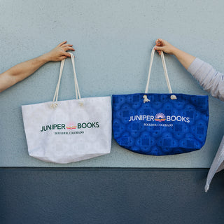 A neutral and blue book club bag held up against a light blue wall