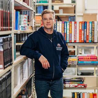 Model wearing full zip hoodie in navy standing against shelves of books