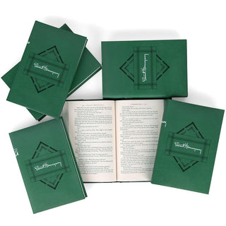 A collection of six green hardcover books by Ernest Hemingway arranged flat on a table. The covers feature a geometric, art deco-style embossed design with Ernest Hemingway's signature in white within a central rectangular frame. One book is open to display print size and surrounded by the front covers of the other books in the series.