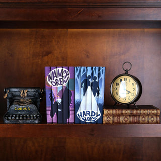 Nancy Drew and Hardy Boys book sets beautifully displayed on a wooden shelf. The spines of each set feature custom illustrations: Nancy Drew’s books depict a silhouette of the iconic detective with bold lettering, while Hardy Boys’ books show two figures against a snowy forest backdrop. The sets are arranged between a vintage typewriter and an antique clock, with classic leather-bound books adding a nostalgic touch. The scene combines modern design with timeless charm, perfect for literary collectors.