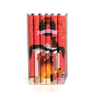 Christmas Classics 2026 book set by Juniper Books, six spines forming a fireside scene with stockings on the mantel.