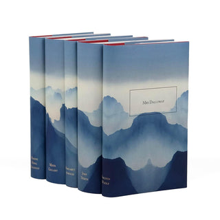 A set of five hardcover books is displayed in a row, each featuring a dust jacket with a blue-toned mountain landscape design that extends seamlessly across all the covers. The book in the foreground is titled Mrs Dalloway by Virginia Woolf, with the title enclosed in a simple rectangular frame. The other books in the set are authored by Joan Didion, Margaret Atwood, Mavis Gallant, and Maxine Hong Kingston, with their names subtly printed on the spines.