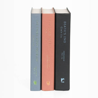 Unjacketed book spines in The Three-Body Problem by Cixin Liu.  From left to right spines are light blue, blush, and black.