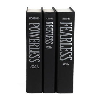 The image shows three hardcover books standing upright with black covers and silver lettering on the spines. The books are authored by Lauren Roberts and published by Simon & Schuster. The titles of the books, from left to right, are "Powerless," "Reckless," and "Fearless." The spines have a uniform design, with bold, capitalized text oriented vertically.